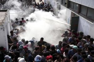 Policemen try to disperse hundreds of migrants by spraying them with fire extinguishers, during a registration procedure which was taking place at the stadium of Kos town, on the southeastern island of Kos, Greece, Tuesday, Aug. 11, 2015. Fights broke out among migrants on the Greek island of Kos Tuesday, where overwhelmed authorities are struggling to contain increasing numbers of people arriving clandestinely on rubber dinghies from the nearby Turkish shore. (ANSA/AP Photo/Yorgos Karahalis)