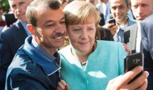 epaselect epa04923489 German Chancellor Angela Merkel (R) has a selfie taken with a refugee during a visit to a refugee reception centre in Berlin, Germany, 10 September 2015. Germany can deal with the arrival of hundreds of thousands of refugees without cutting social welfare benefits or raise taxes, Vice Chancellor Sigmar Gabriel said on 10 September, during a debate in parliament on next year's budget. Germany expects 800,000 asylum seekers this year, four times more than last year and more than any other country in the European Union, which is split on how to deal with the biggest refugee crisis since World War II. EPA/BERND VON JUTRCZENKA