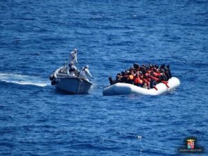 Italian Navy personnel, left, approach a rubber dinghy filled with migrants in the Sicily channel, Mediterranean Sea, Friday, March 18, 2016. The Italian navy rescued Friday 486 migrants in the Sicily channel, while they were trying to cross the Mediterranean sea to reach Italian coasts. Italian officials say good weather is the main factor behind a spike in migrant crossings from Libya, with mostly Italian ships picking up 3,100 migrants over the last three days. (Italian Navy via AP Photo)